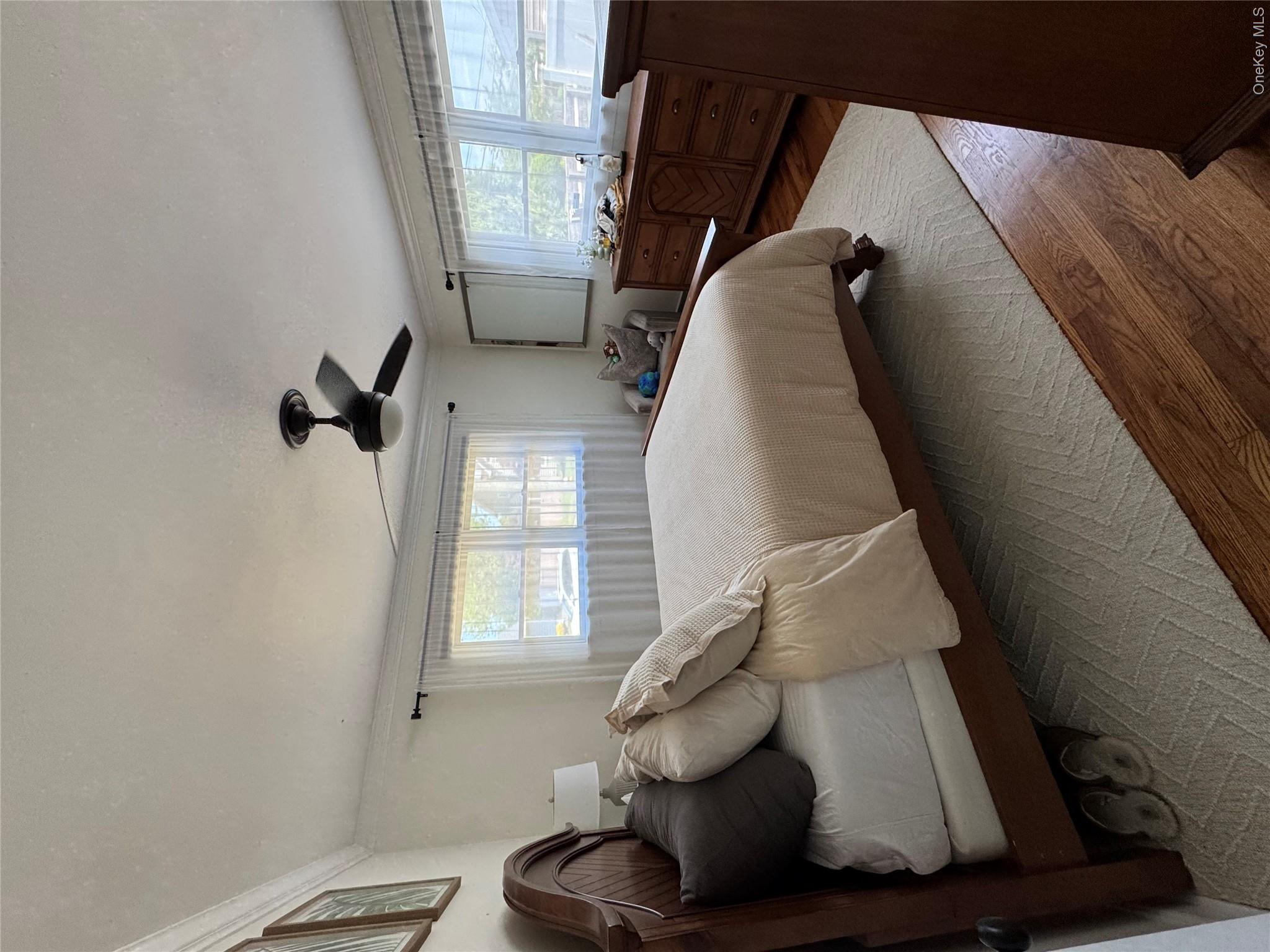 338 Carnation Road West Islip, NY 11795 - Photo 8 of 18 Bright sunlit bedroom room featuring two windows, crown molding, wood-finish flooring, and a ceiling fan