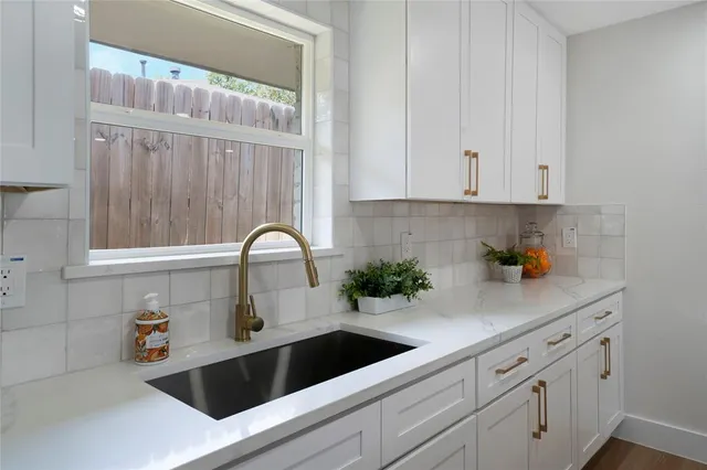 a kitchen with granite countertop white cabinets and a sink