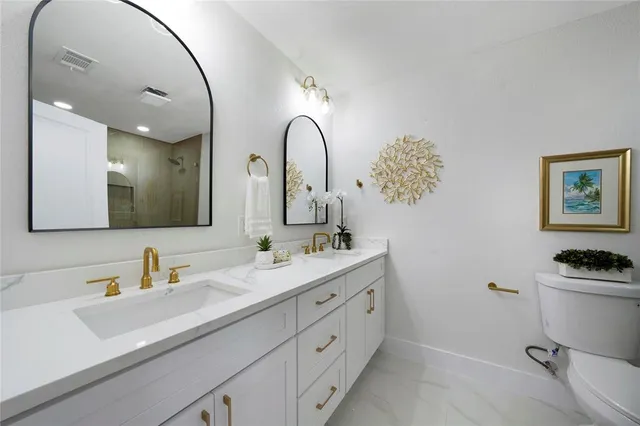 a bathroom with a granite countertop toilet sink and mirror