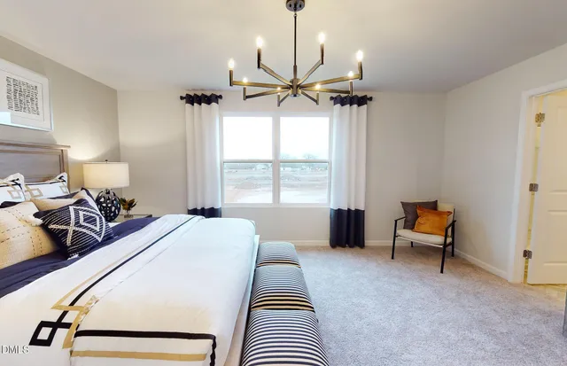 a spacious bedroom with a bed a chandelier and a window