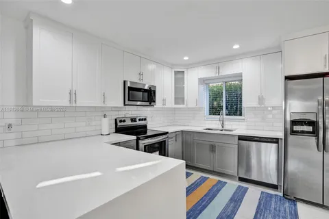 a kitchen with stainless steel appliances granite countertop a sink a stove a refrigerator and cabinets