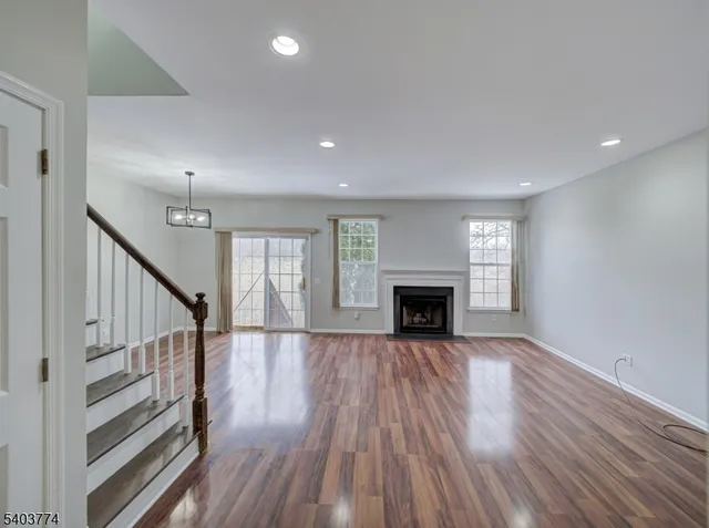a view of an empty room with wooden floor fireplace and a window