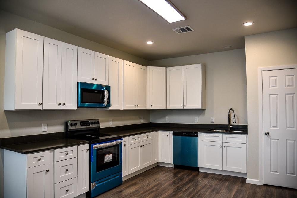 1602 North Mcdonald Avenue Decatur, TX 76234 - Photo 3 of 13 a kitchen with granite countertop white cabinets sink and stainless steel appliances