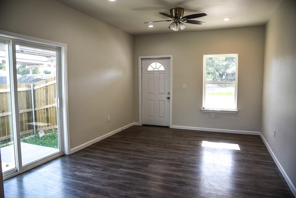 1602 North Mcdonald Avenue Decatur, TX 76234 - Photo 7 of 13 an empty room with wooden floor fan and windows