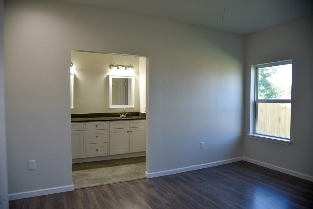 1602 North Mcdonald Avenue Decatur, TX 76234 - Photo 10 of 13 an empty room with wooden floor and windows