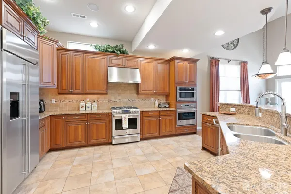 a large kitchen with stainless steel appliances granite countertop a stove a sink and a refrigerator