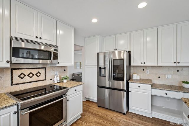 a kitchen with stainless steel appliances a refrigerator a stove and white cabinets