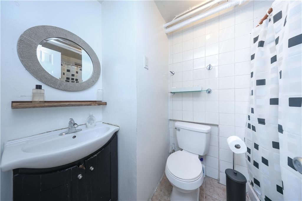 1200 East 49th Street Brooklyn, NY 11234 - Photo 18 of 30 a bathroom with a toilet a sink and mirror