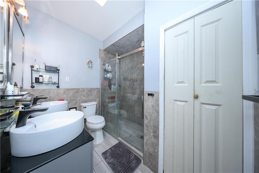 1200 East 49th Street Brooklyn, NY 11234 - Photo 23 of 30 a bathroom with a sink a toilet a mirror and shower