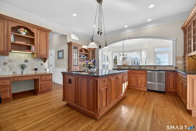 a kitchen with stainless steel appliances kitchen island granite countertop wooden floors and white cabinets