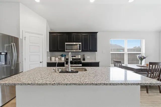 a kitchen with granite countertop a sink a counter top space appliances and cabinets