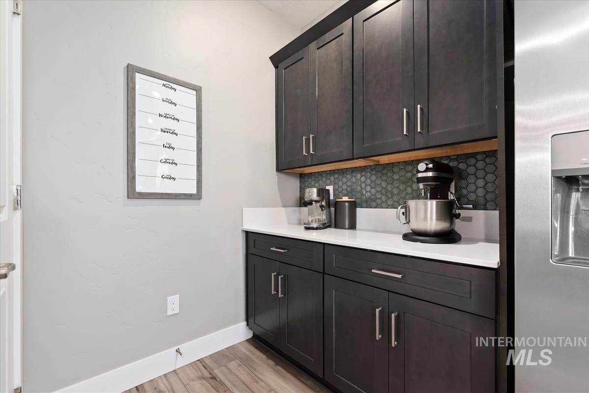 815 Knowledge Street Middleton, ID 83644 - Photo 13 of 49 Dark wood-finish cabinetry with brushed nickel hardware, white countertops, and a green hexagonal tile backsplash