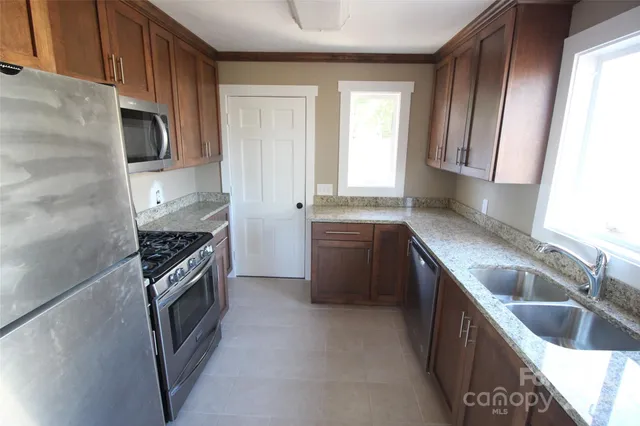 a kitchen with stainless steel appliances granite countertop a sink stove and refrigerator