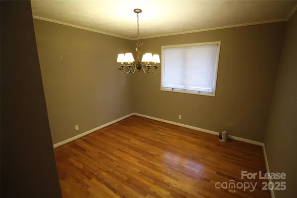 a view of a room with wooden floor and chandelier