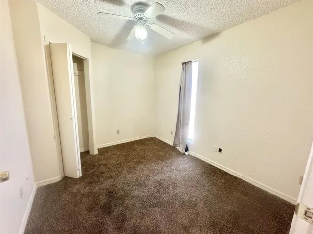 an empty room with a ceiling fan and a window