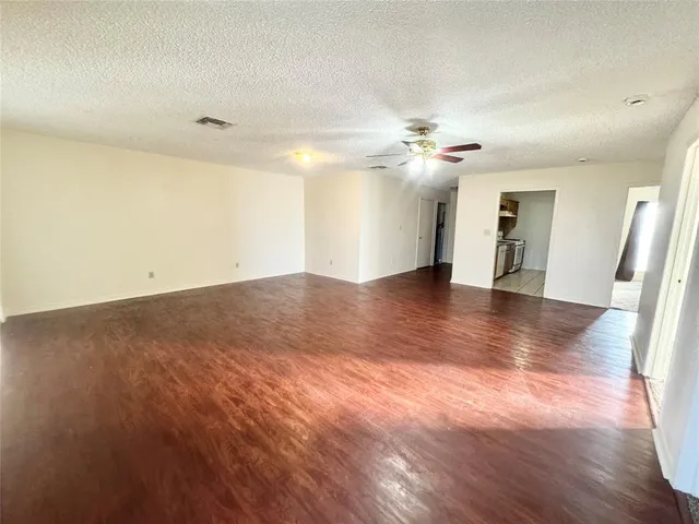 an empty room with wooden floor and ceiling fan