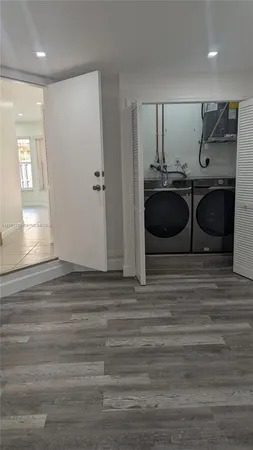 an empty room with wooden floor closet and windows