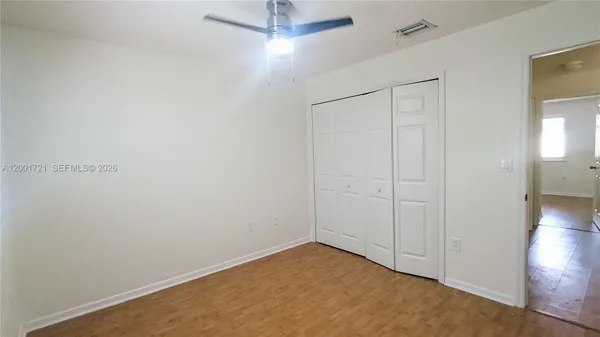 an empty room with wooden floor fan and windows