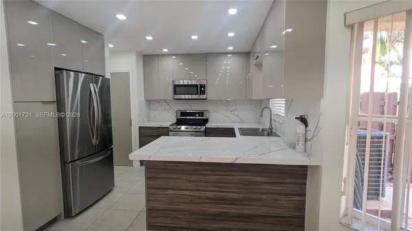 a kitchen with stainless steel appliances kitchen island granite countertop a refrigerator and a stove top oven