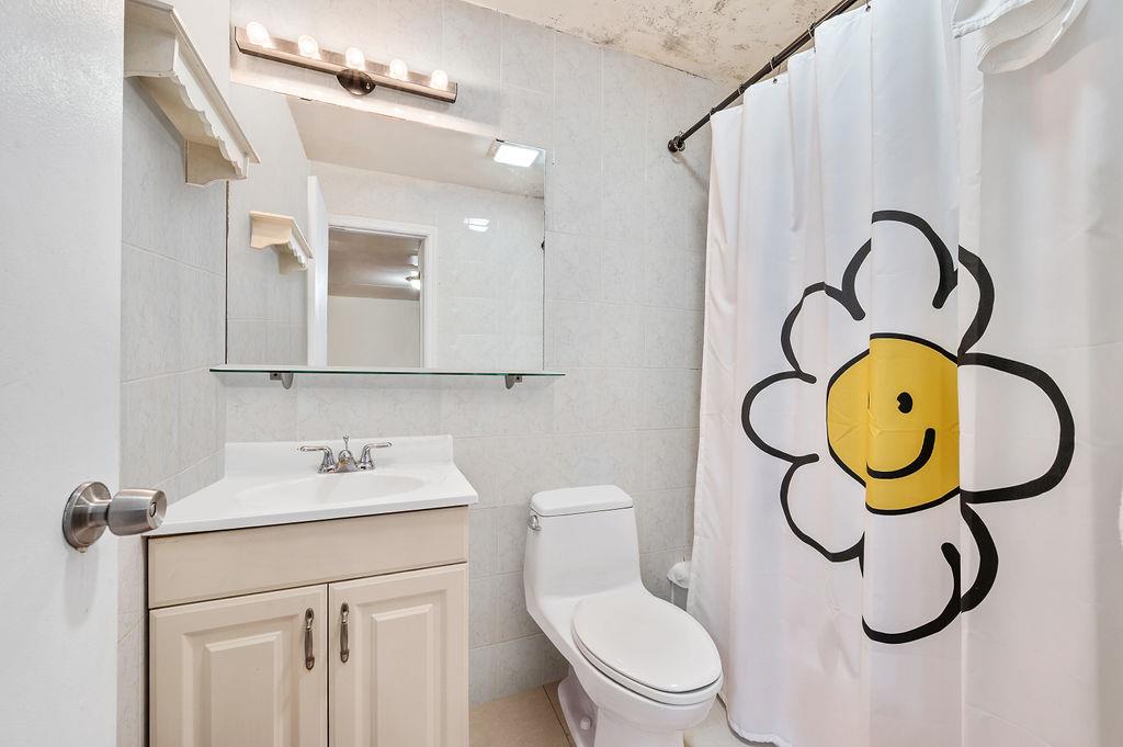 43-07 162nd Street Queens, NY 11358 - Photo 11 of 18 Full bathroom featuring toilet, a shower with curtain, vanity, and tile walls