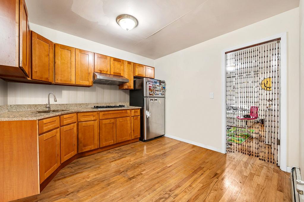 43-07 162nd Street Queens, NY 11358 - Photo 14 of 18 Kitchen with light wood-style flooring, a sink, freestanding refrigerator, brown cabinets, and under cabinet range hood