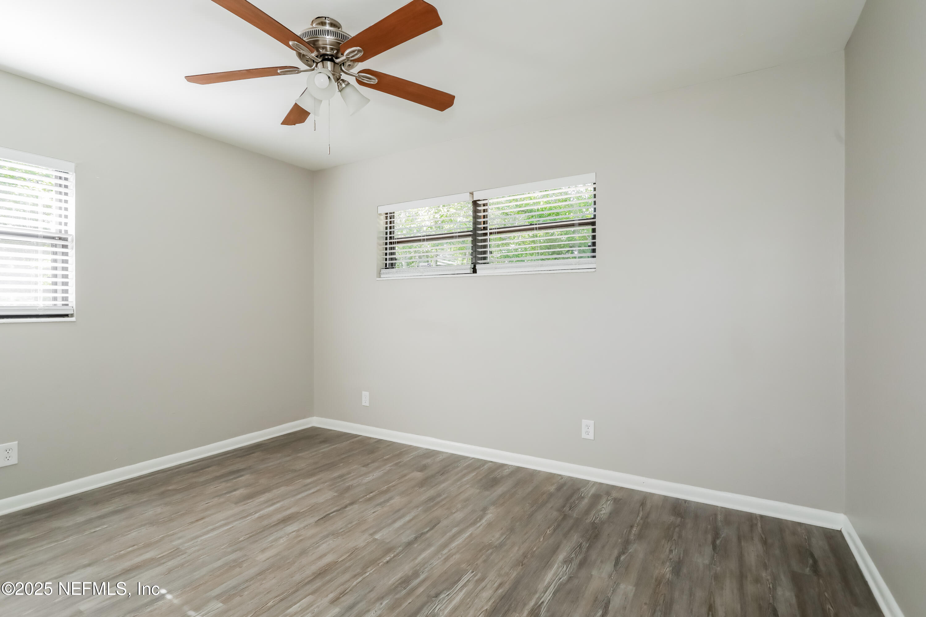 7428 Centauri Road Jacksonville, FL 32210 - Photo 9 of 15 an empty room with wooden floor ceiling fan and windows