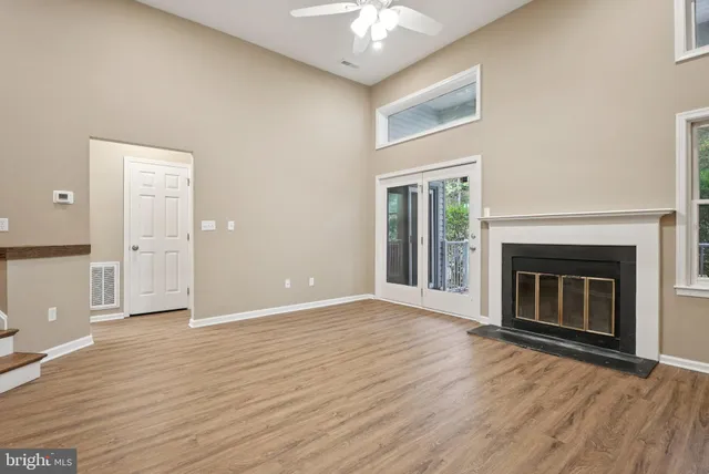 an empty room with wooden floor fireplace and windows