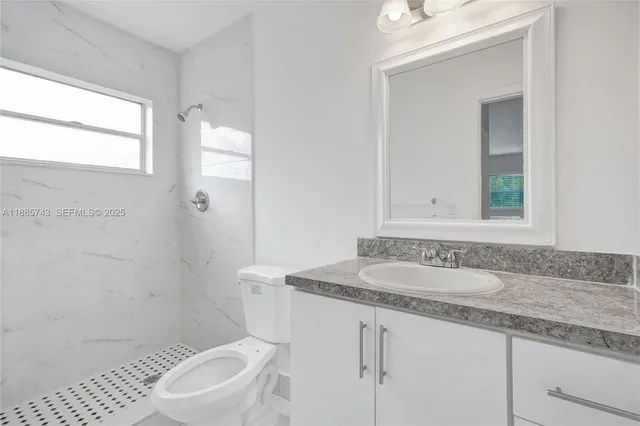 a bathroom with a granite countertop sink a mirror and a toilet