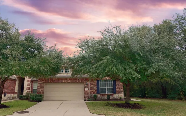 a front view of a house with a garden and tree