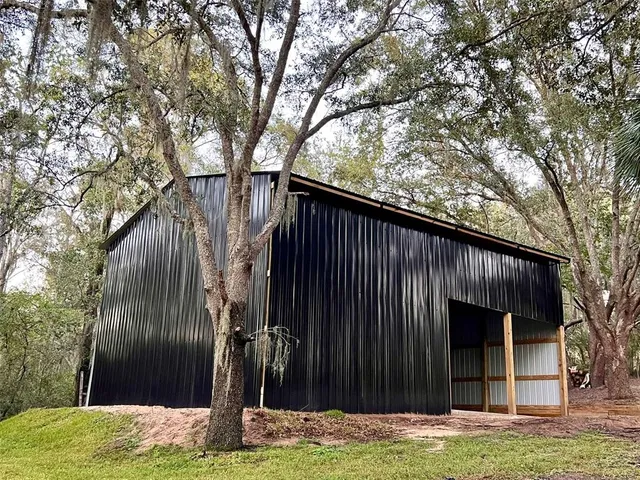 a view of a house with a yard and large tree