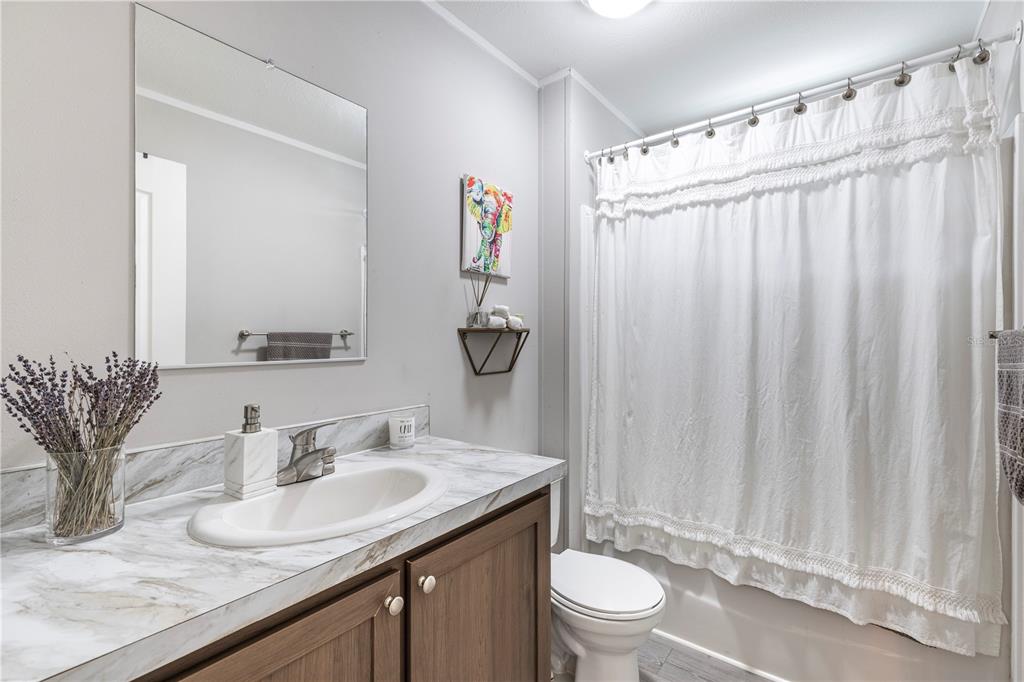 10135 North Em En El Grove Road Leesburg, FL 34788 - Photo 22 of 54 a bathroom with a granite countertop sink a toilet and a mirror