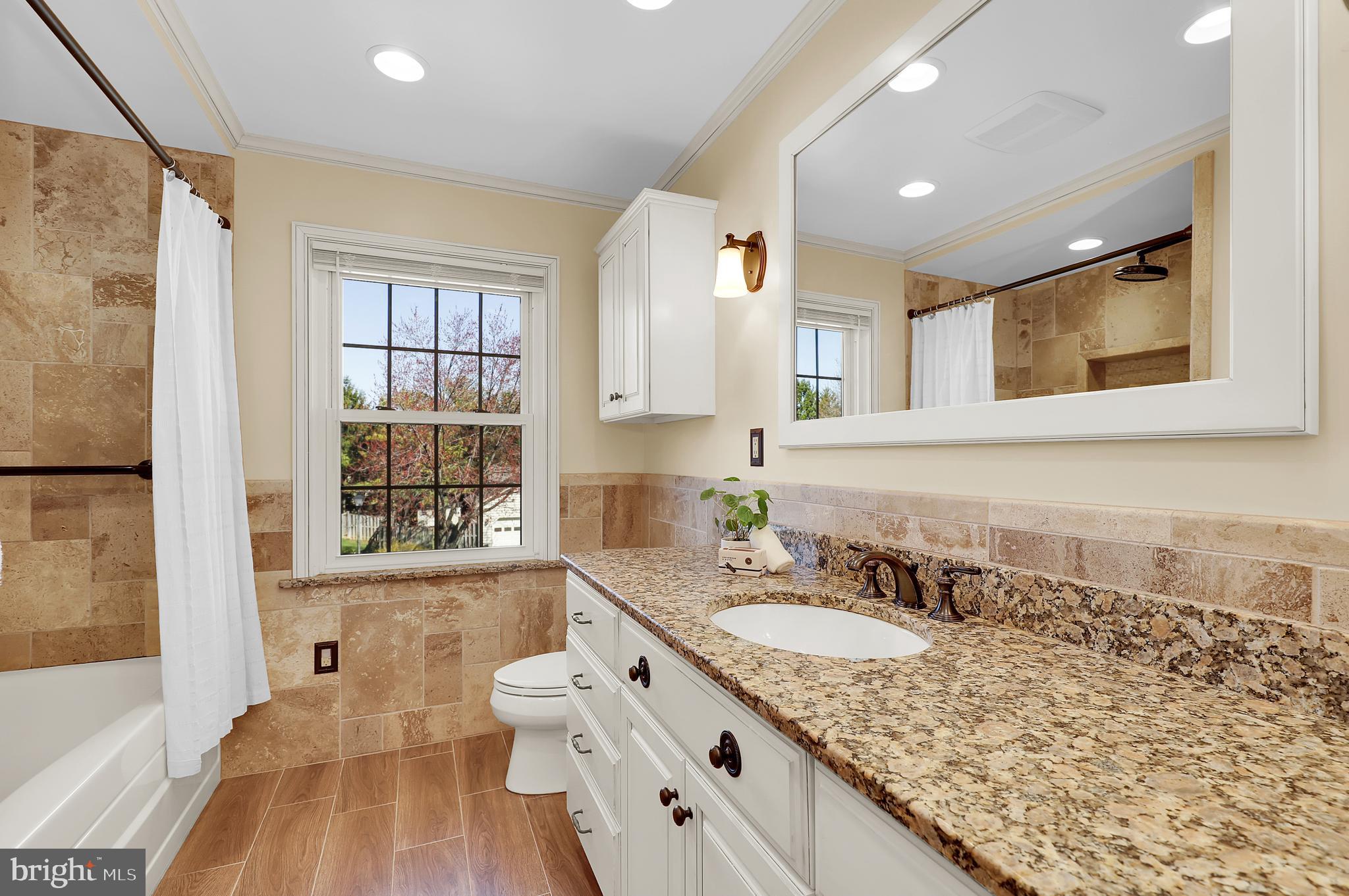 7908 River Run Court Frederick, MD 21701 - Photo 29 of 59 a bathroom with a granite countertop sink mirror and a bathtub