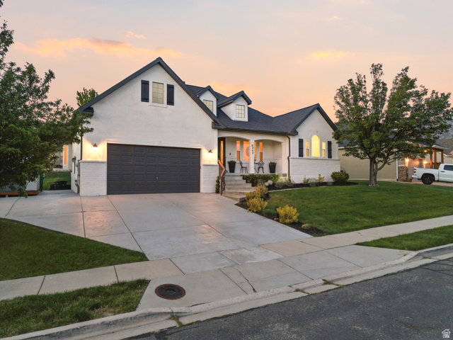 6242 Apollo Way Highland, UT 84003 - Photo 2 of 47 Modern farmhouse-style residence featuring a white stucco and brick exterior, a dark shingle roof, and a two-car garage