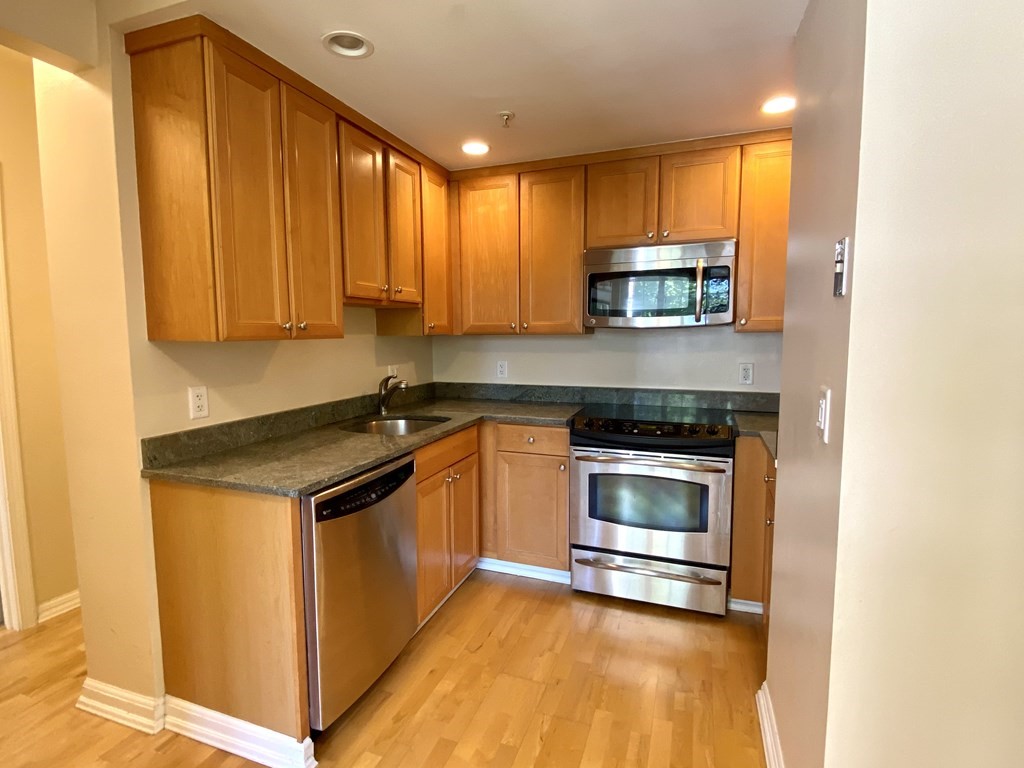 a kitchen with granite countertop cabinets stainless steel appliances and a window