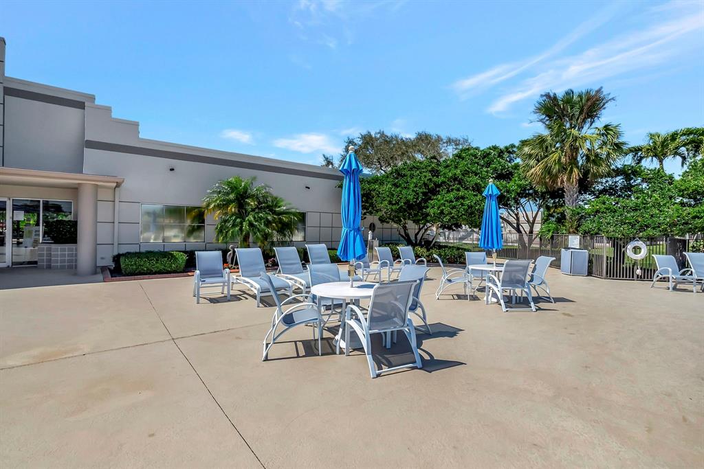 19000 Stewart Circle, Unit 4 Boca Raton, FL 33496 - Photo 61 of 63 a view of a patio with dining table and chairs under an umbrella