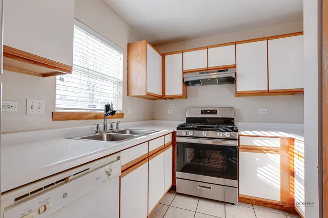 a kitchen with granite countertop a sink stainless steel appliances white cabinets and a window