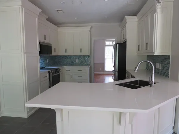 a kitchen with granite countertop white cabinets and stainless steel appliances