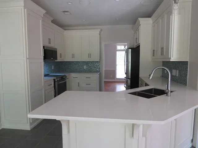 a kitchen with granite countertop white cabinets and stainless steel appliances