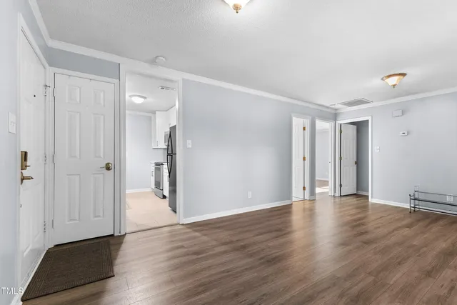 a view of an empty room with wooden floor and a window