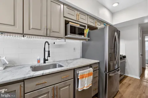 a kitchen with stainless steel appliances granite countertop a refrigerator a sink and white cabinets
