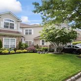 a front view of a house with a garden and trees