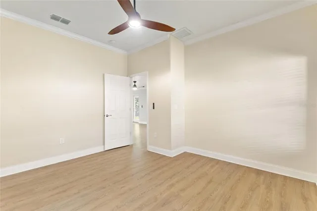 an empty room with wooden floor and ceiling fan