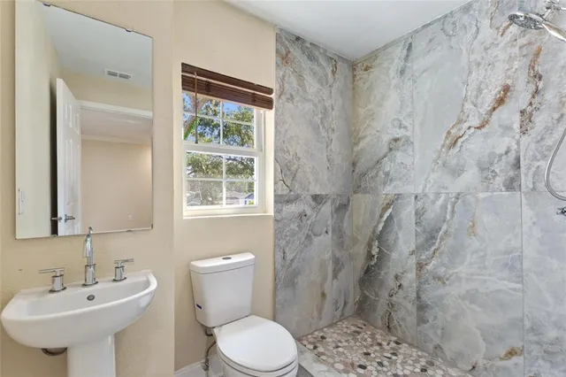 a bathroom with a sink a toilet and shower