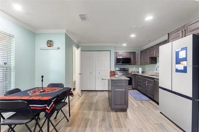 a kitchen with stainless steel appliances granite countertop a refrigerator a stove top oven a sink dishwasher a dining table and chairs with wooden floor