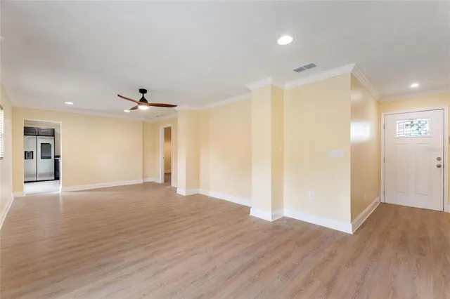 a view of an empty room with wooden floor and a ceiling fan