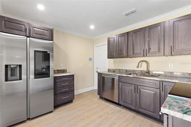 a kitchen with stainless steel appliances granite countertop a refrigerator and a sink