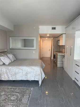 a bedroom with a bed and a refrigerator