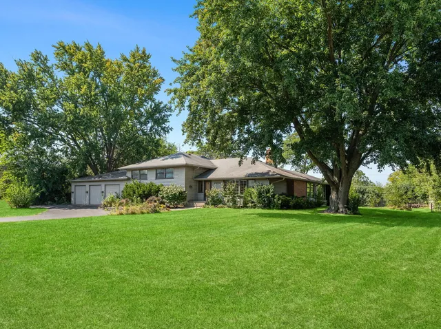 a view of a house with a big yard and large trees
