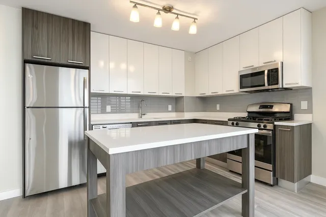 a living room with stainless steel appliances furniture and a kitchen view