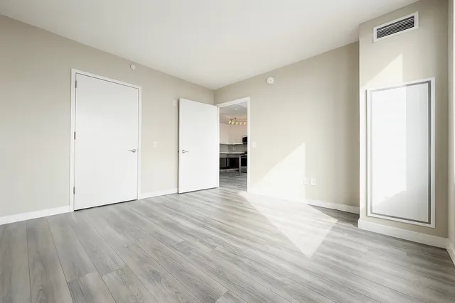 an empty room with wooden floor and windows